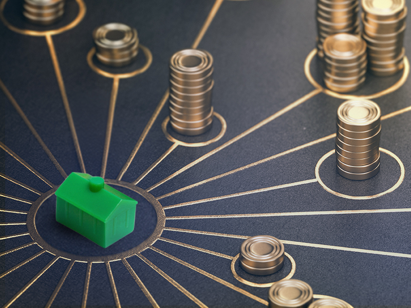 A monopoly style toy house at the centre of stacks of gold coins. Representing property finance diversity.