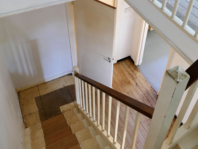 A photo of a staircase in a house with bare floorboards.